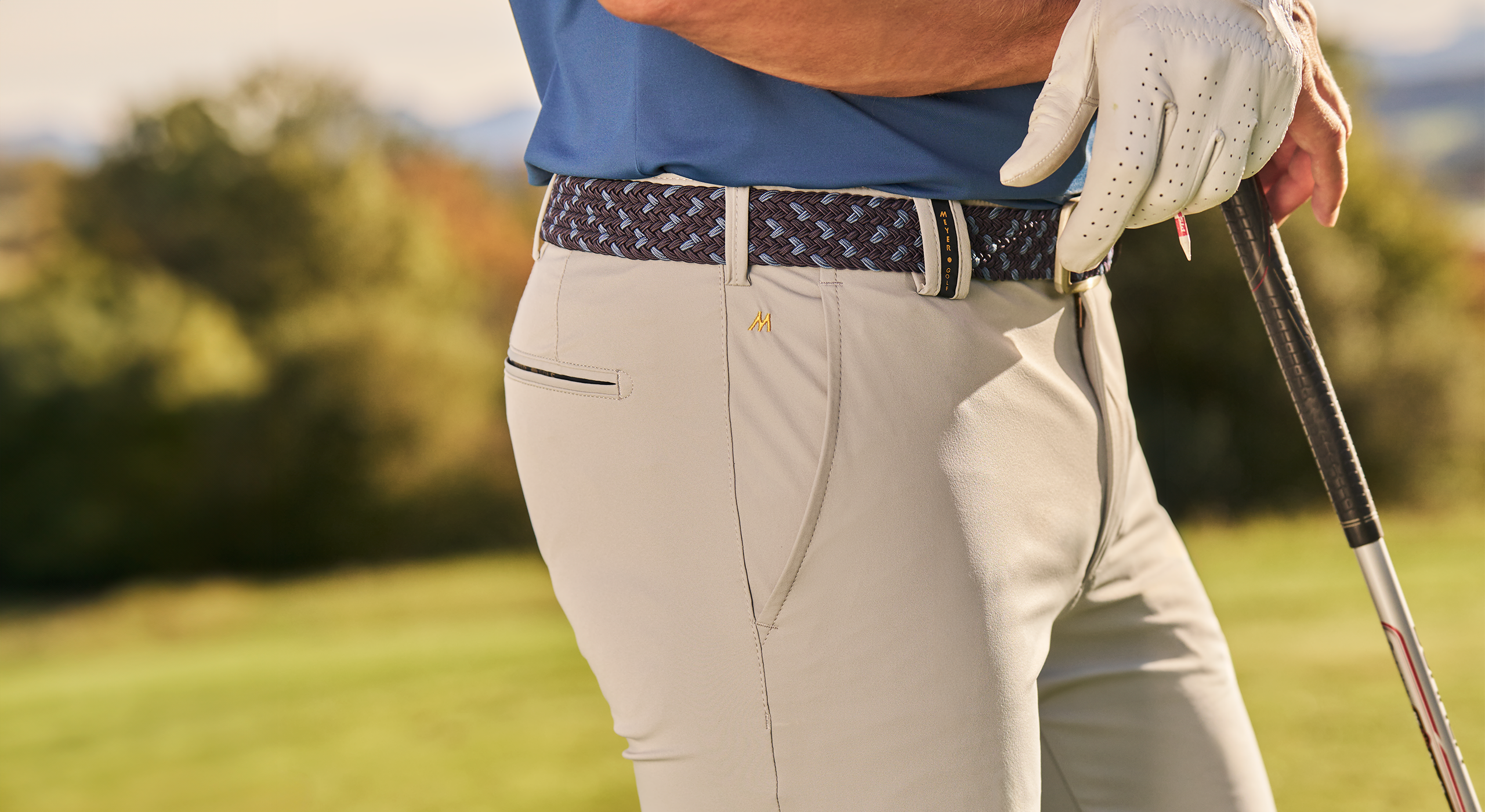 Person wearing golf attire with a golf club on a blurred golf course background