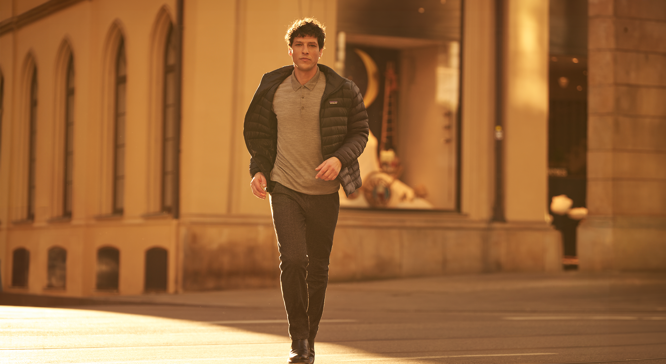 Man walking in a sunlit urban setting with architectural background